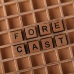 Wooden tiles spelling 'forecast' arranged on a wooden grid, perfect for business or prediction themes.