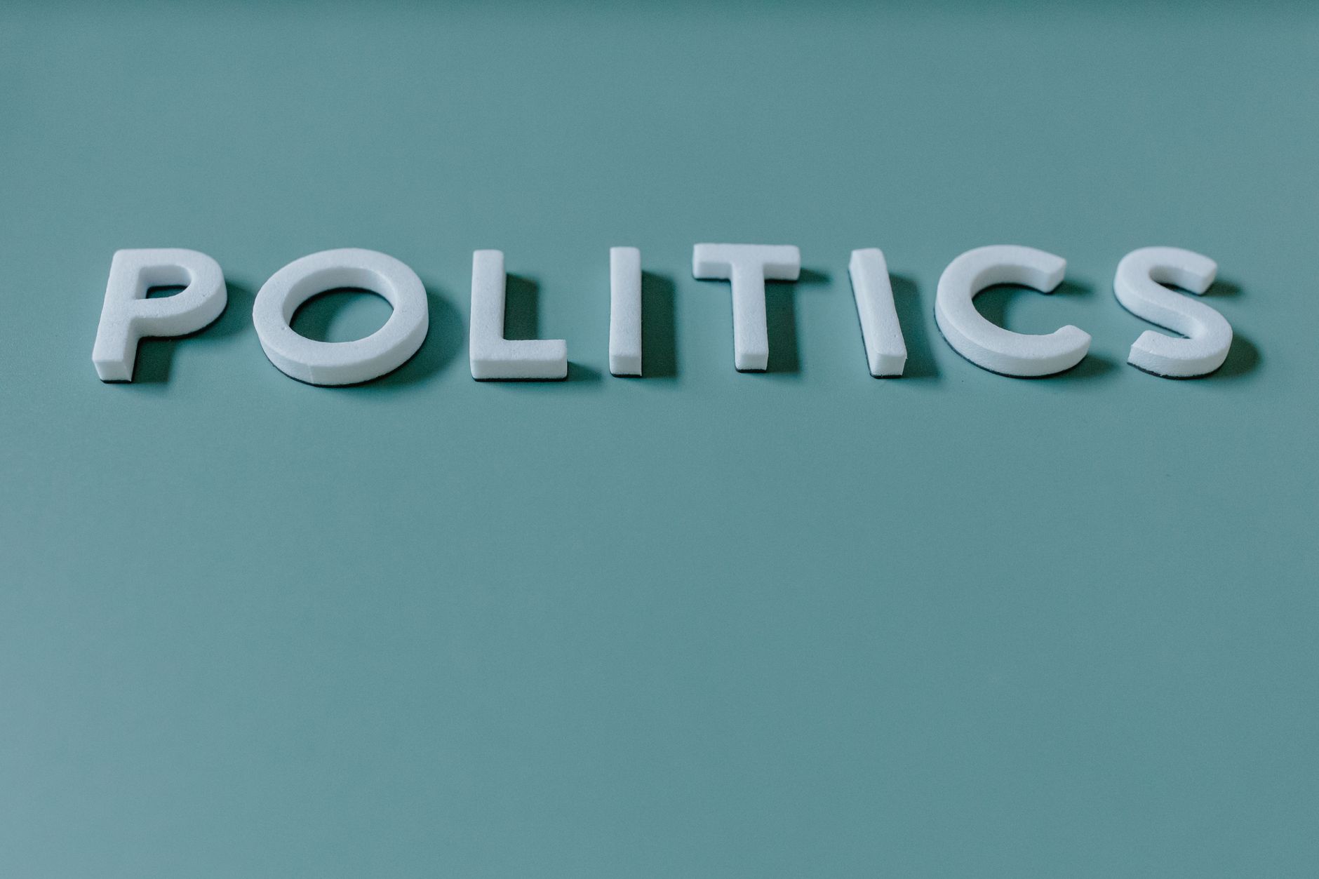 Close-up image of the word 'Politics' against a teal green background, highlighting political themes.