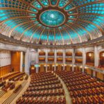 Vibrant interior of a parliament hall with a grand dome and intricate architecture.