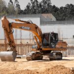 A large excavator positioned at an active construction site with clear skies.