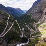 Aerial view of the winding Trollstigen road surrounded by lush mountains in Norway.