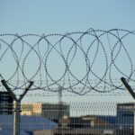 Security fence with barbed wire under clear blue sky in Tallinn, Estonia.