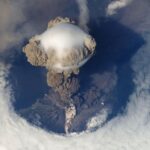 Stunning bird's eye view of a volcanic eruption with massive ash cloud and smoke plumes.