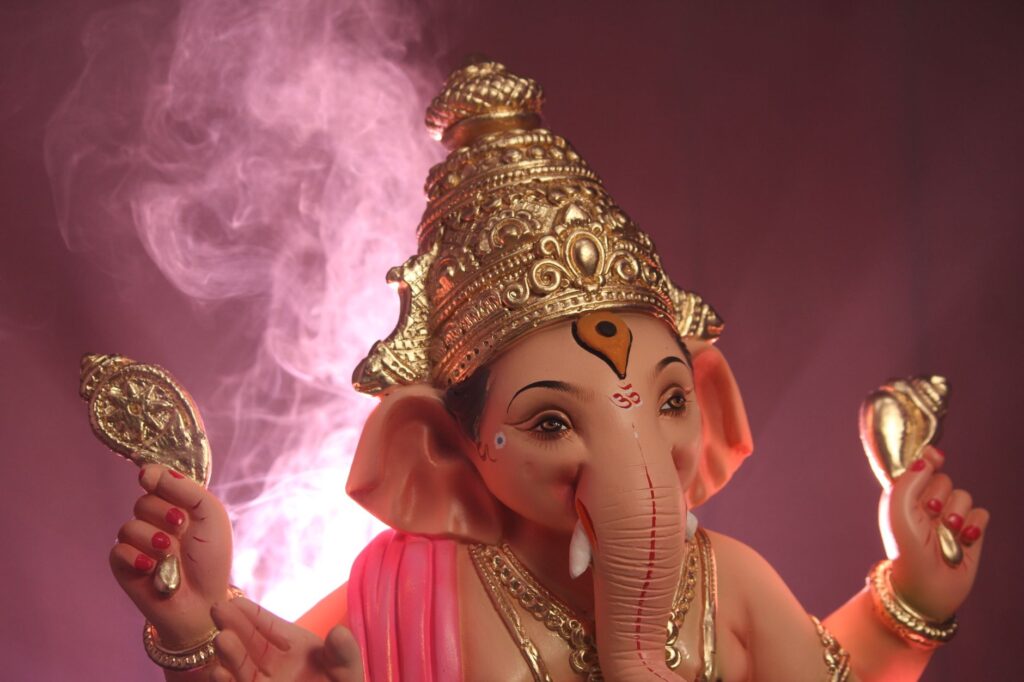 Close-up of a detailed Ganesha statue surrounded by pink smoke, symbolizing spirituality.