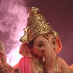 Close-up of a detailed Ganesha statue surrounded by pink smoke, symbolizing spirituality.