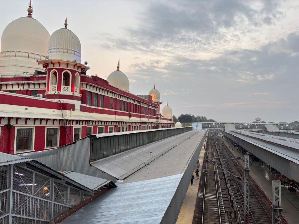 Aerial view of a classic Indian railway station with red architecture and domes at dusk.