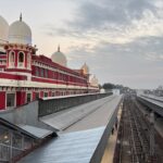 Aerial view of a classic Indian railway station with red architecture and domes at dusk.