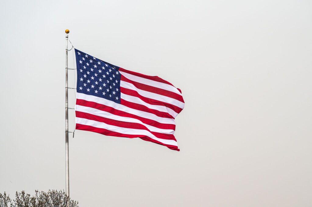 A striking image of the American flag waving on a flagpole set against a clear sky.