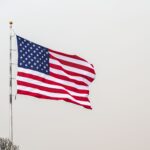 A striking image of the American flag waving on a flagpole set against a clear sky.