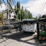 Utility crew working on damaged power lines after accident on a city street with a white van involved.