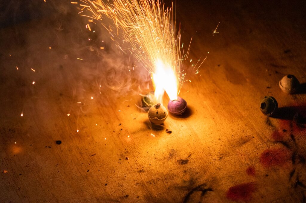 Close-up of colorful firework sparks illuminating the dark wooden surface.