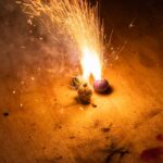 Close-up of colorful firework sparks illuminating the dark wooden surface.