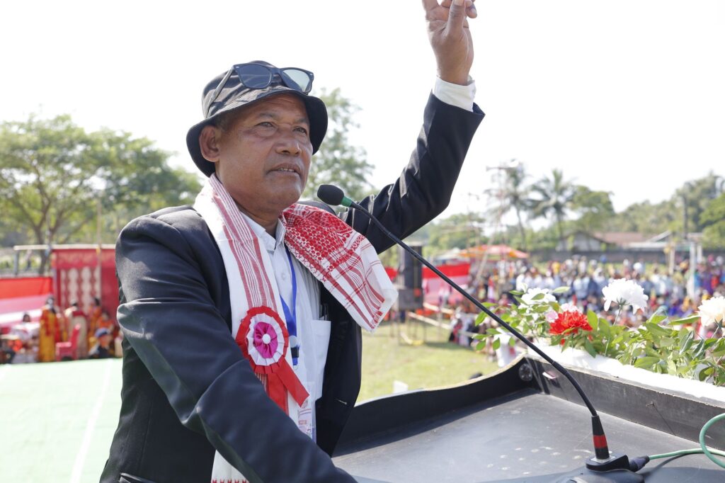 An Asian man giving a speech at an outdoor rally, gesturing with his hand.