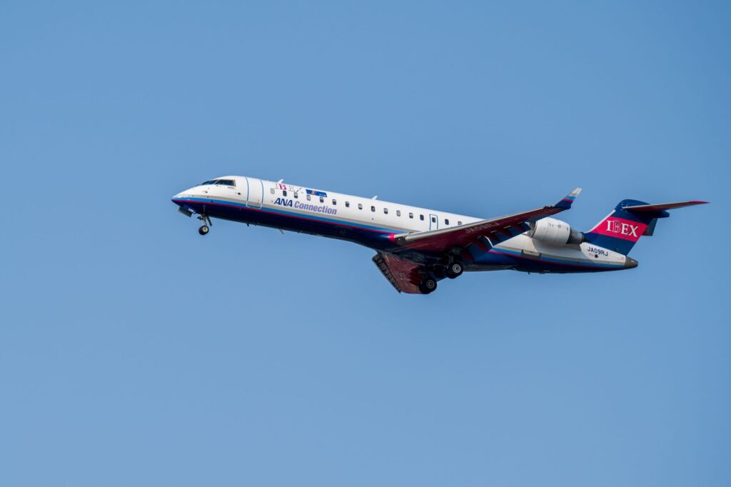 A commercial airplane of IBEX Airlines in flight against a bright blue sky, showcasing aviation travel.
