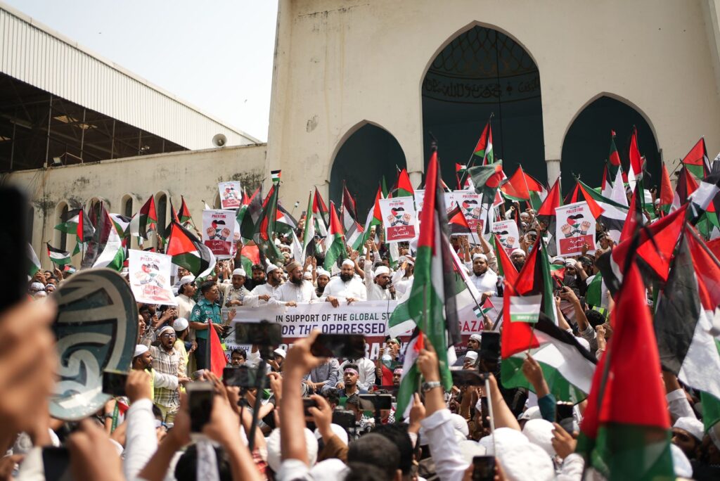 Large Pro-Palestinian demonstration in Dhaka with flags and banners supporting freedom and solidarity.