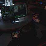 A group of people in a dark room working on computers, related to cybersecurity.