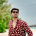 Fashionable man wearing sunglasses poses on a sunny Maldives beach.