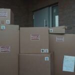 Several cardboard packages marked as fragile stacked at a building entrance.