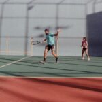 Dynamic tennis match on an outdoor court with a man and woman in action.