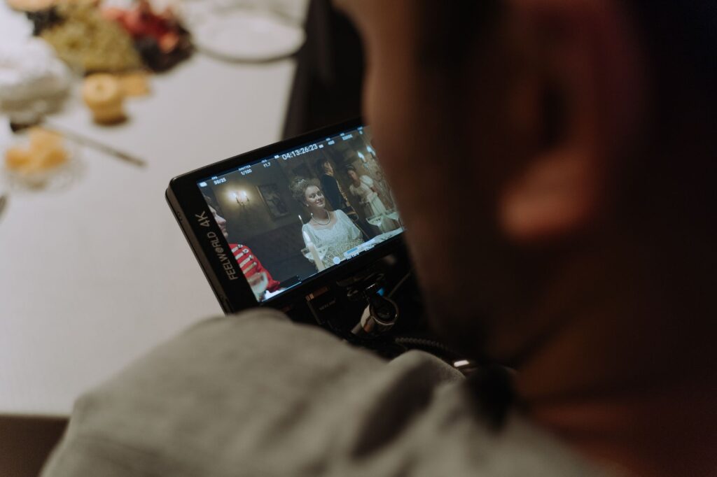 A filmmaker reviews a scene on a monitor during a film shoot dinner scene.