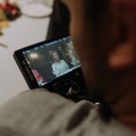 A filmmaker reviews a scene on a monitor during a film shoot dinner scene.