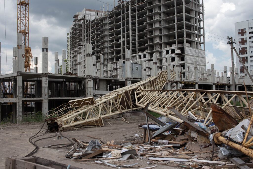 An urban construction site featuring a collapsed crane and unfinished buildings under cloudy skies.