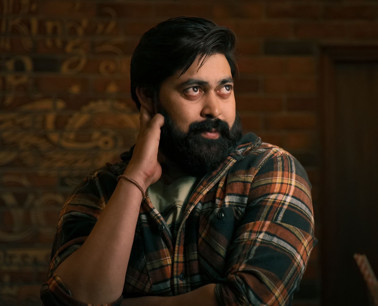 Captivating portrait of a bearded man in a plaid shirt indoors, exuding a thoughtful demeanor.
