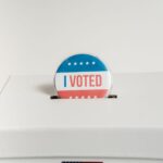 Close-up of an I Voted badge on a ballot box, symbolizing voting in the USA elections.