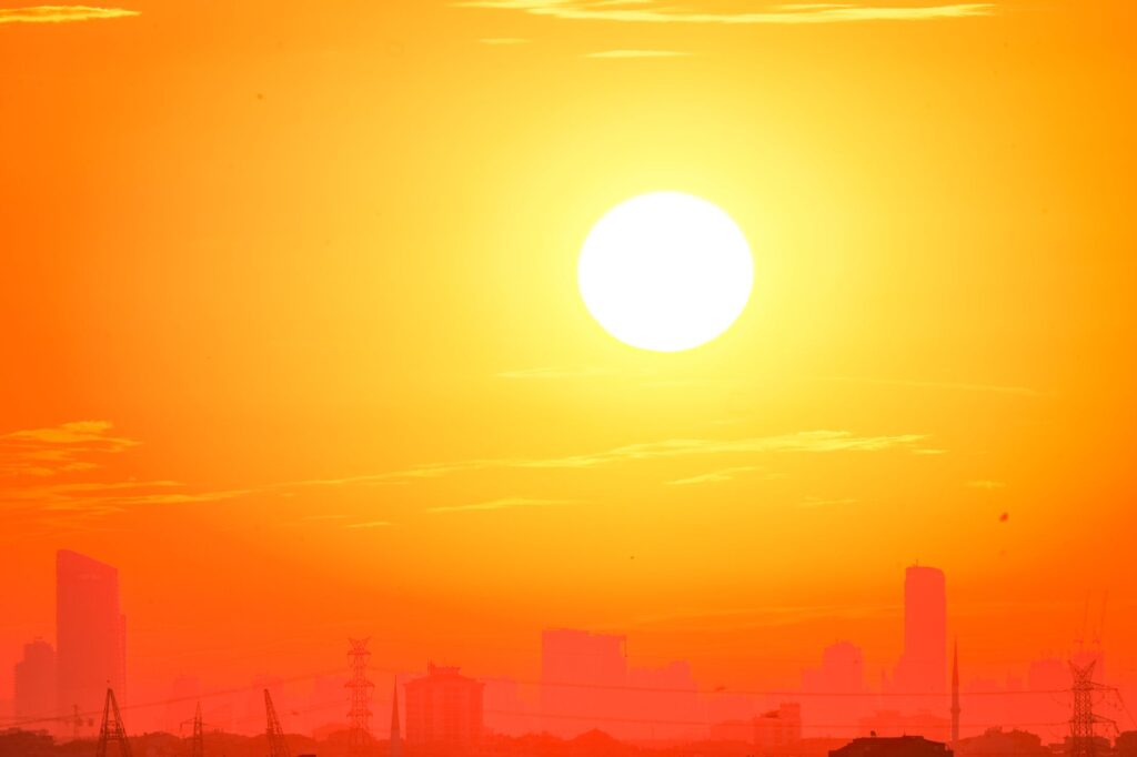 A city skyline silhouetted against a vivid, orange sunset sky.