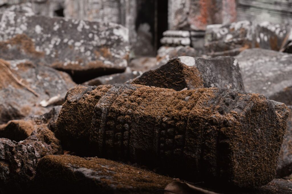 Close-up of moss-covered stone ruins at Angkor site in Cambodia, showcasing intricate ancient carvings.