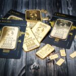 A collection of fine gold bars displayed on a textured wooden surface.