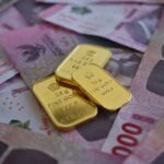 Close-up of gold bars on Thai baht banknotes, symbolizing wealth and prosperity.