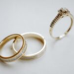 Elegant gold wedding bands and a diamond engagement ring on a plain background, ideal for wedding themes.