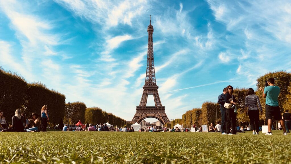 A sunny day in Paris with people relaxing in a park near the Eiffel Tower, showcasing urban leisure.