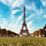 A sunny day in Paris with people relaxing in a park near the Eiffel Tower, showcasing urban leisure.