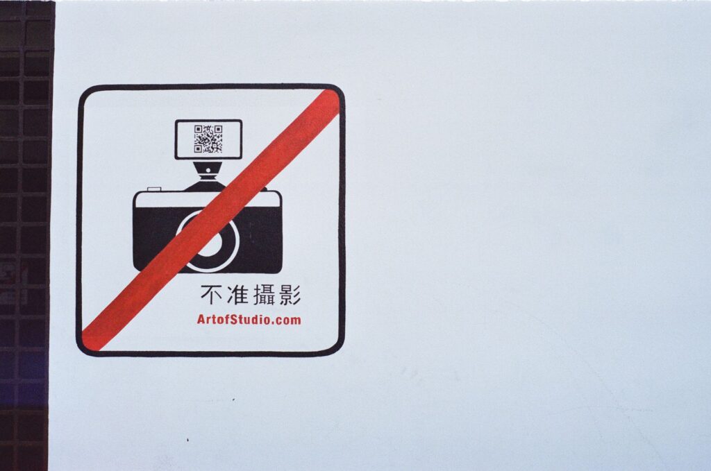 Sign prohibiting photography with a camera icon and QR code in red circle.