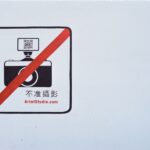 Sign prohibiting photography with a camera icon and QR code in red circle.