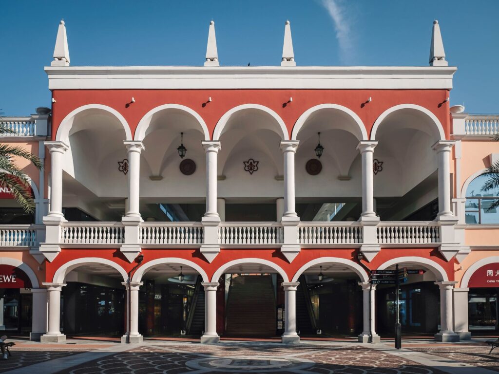 Elegant colonial-style building with red and white arches and clear blue sky.