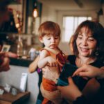 Heartwarming moment of a grandmother holding a child at a family gathering indoors.