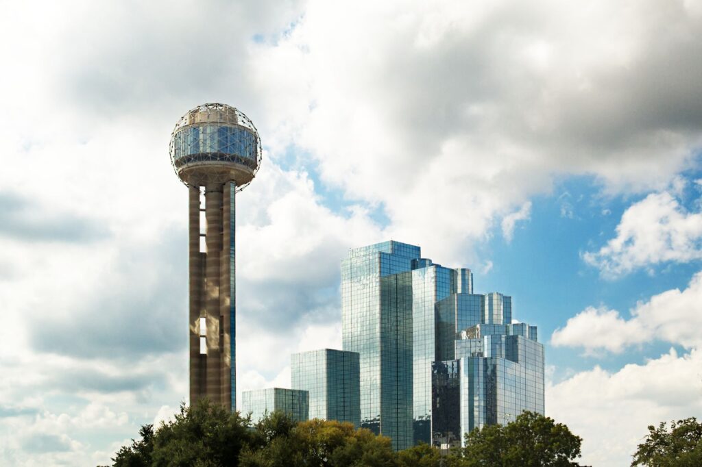 Reunion Tower and modern skyscrapers in Dallas, Texas against a cloudy sky.