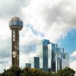 Reunion Tower and modern skyscrapers in Dallas, Texas against a cloudy sky.