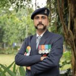 A police officer in uniform proudly displays his medals in a serene outdoor setting, exuding authority.