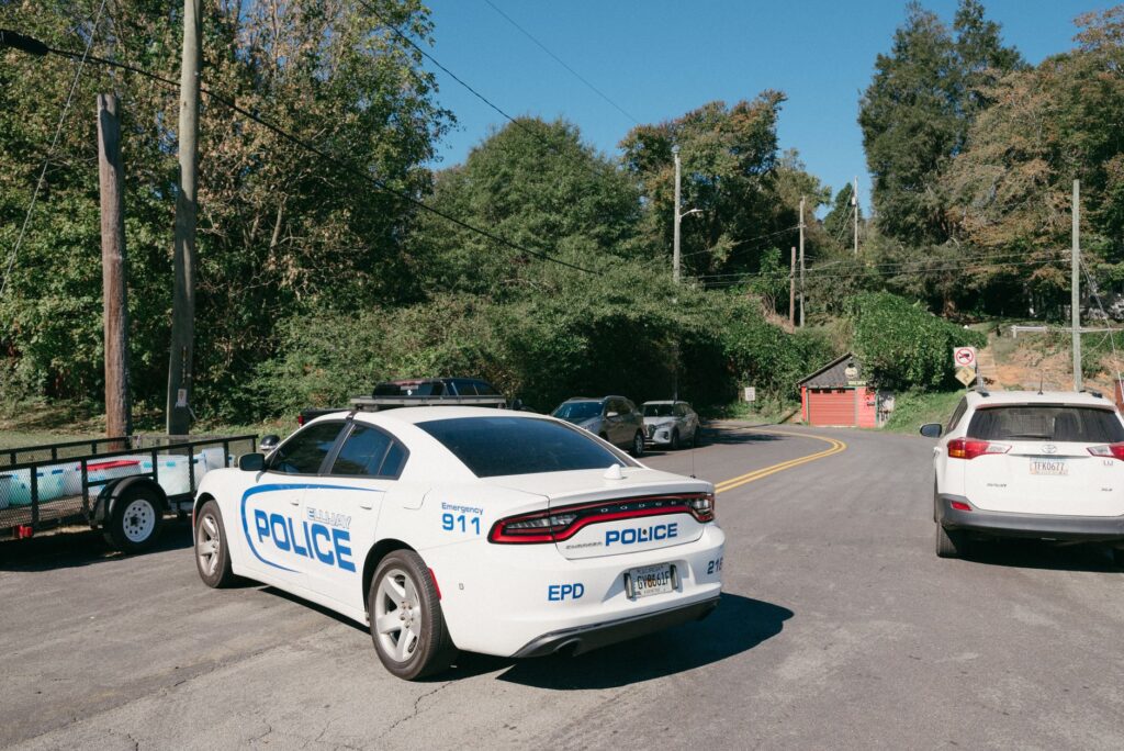 A police car parked at a suburban road intersection on a sunny day.