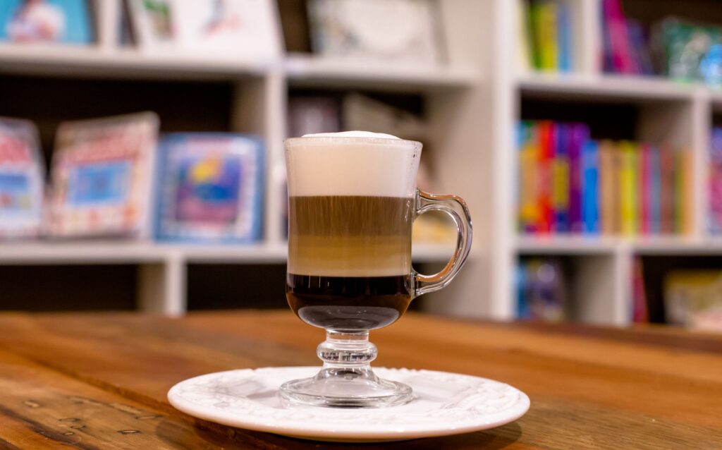 Close-up of a layered coffee in a glass mug on a cafe table, warm and inviting.