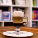 Close-up of a layered coffee in a glass mug on a cafe table, warm and inviting.