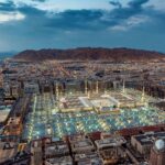 A stunning aerial view of Al-Masjid an-Nabawi in Medina at dusk, showcasing its illuminated grandeur.
