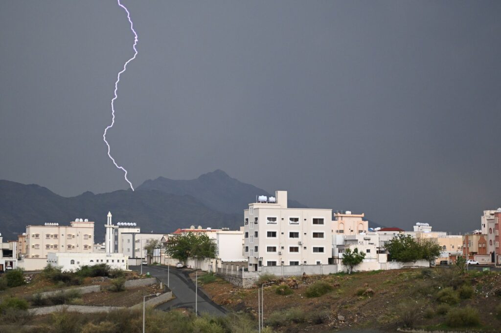 Dramatic lightning bolt over Muhayil city with mountains and storm clouds in Aseer Province, Saudi Arabia.