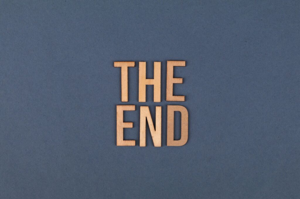 Wooden letters form 'The End' on a plain blue surface, ideal for concluding or finality themes.