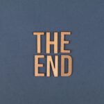 Wooden letters form 'The End' on a plain blue surface, ideal for concluding or finality themes.