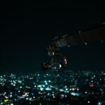 A cinematic drone camera captures a vibrant Indian cityscape at night.